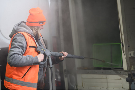 Na fotografii pracownik firmy myjący wózki  